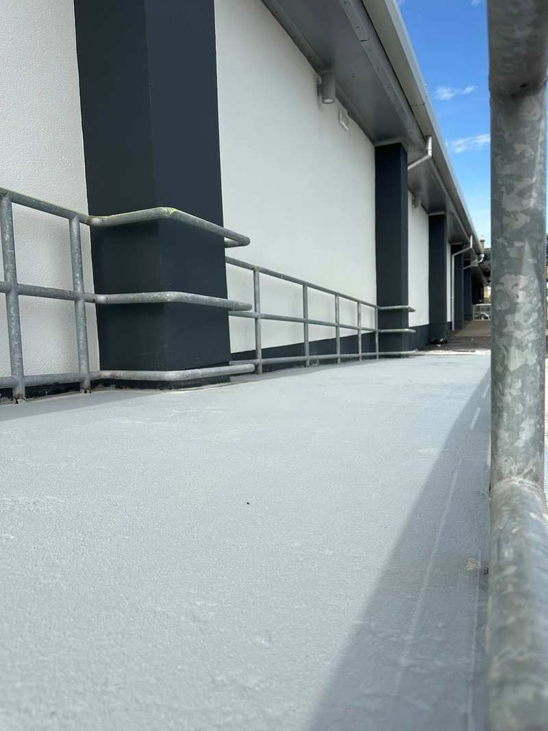 Access ramp finished in pale grey anti-slip MMA resin between galvanised handrails