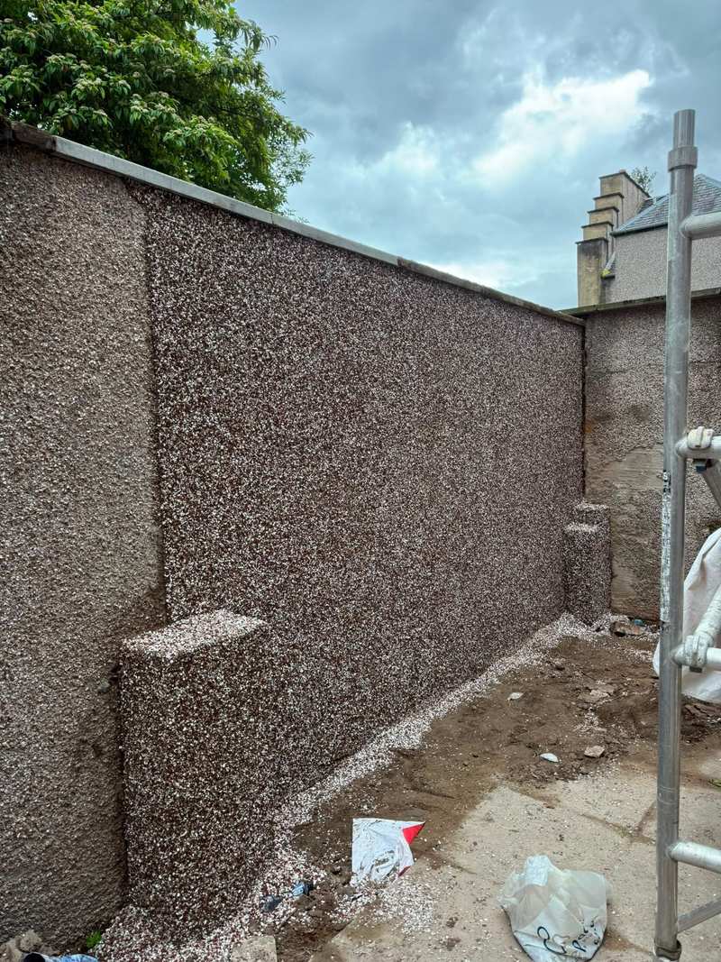 Boundary wall finished in new dry dash roughcast, with scaffold tube still in place