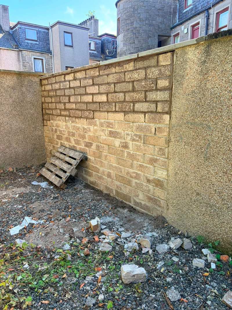 New buff blockwork panel built into a boundary wall between sections of old roughcast
