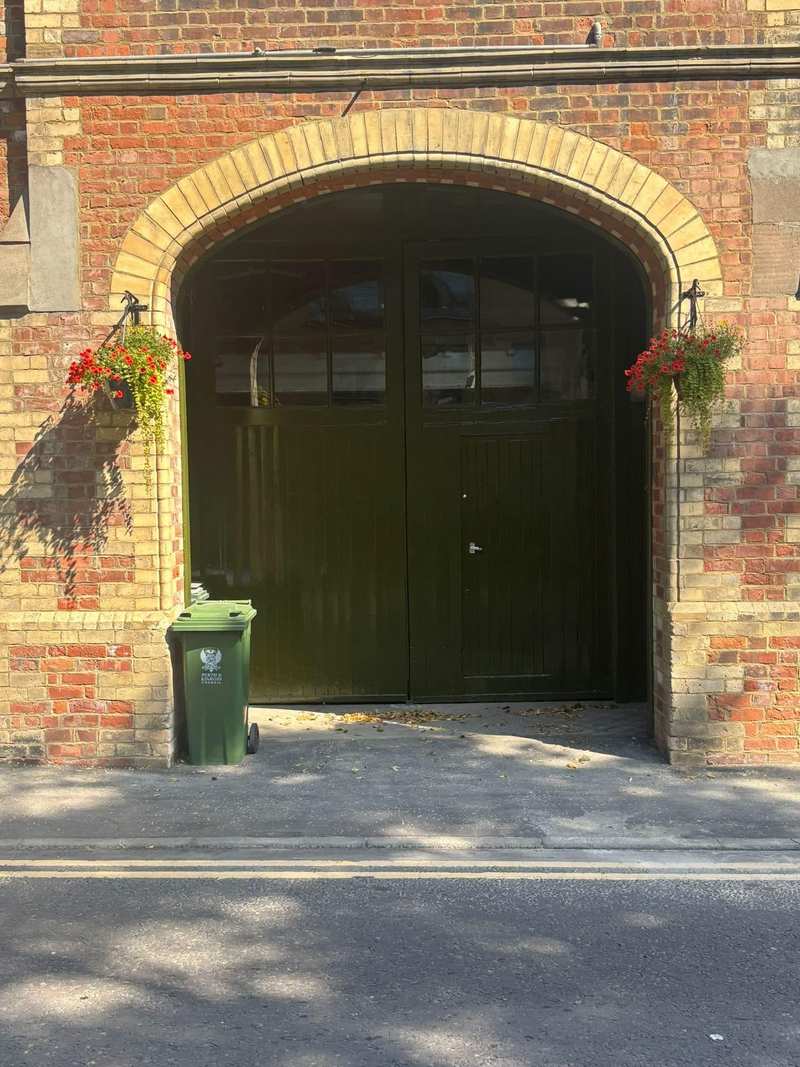 Arched carriage doorway in red brick with a sandstone arch and painted green timber doors