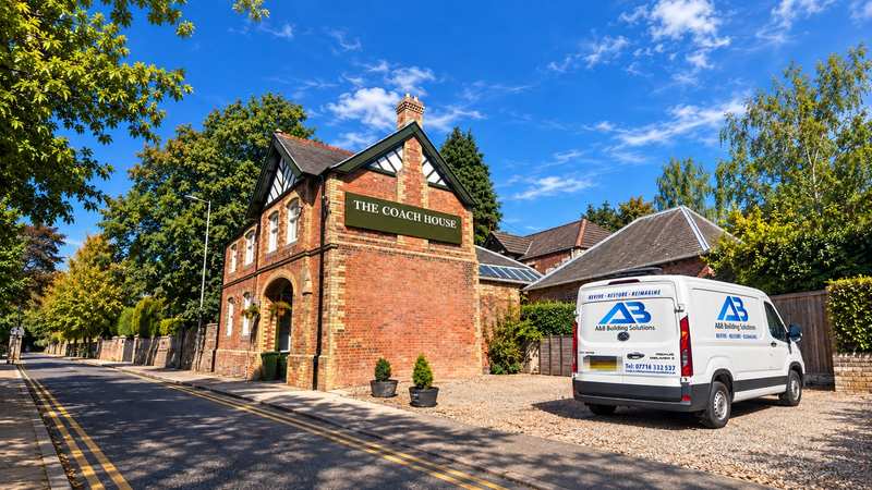 The restored Coach House in Perth, a red brick building with a timber gable and name sign, with the A&B Building Solutions van parked alongside