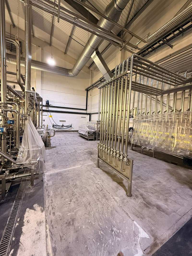 Ground concrete floor beside a stainless steel pipe rack and floor drain, ready for resin