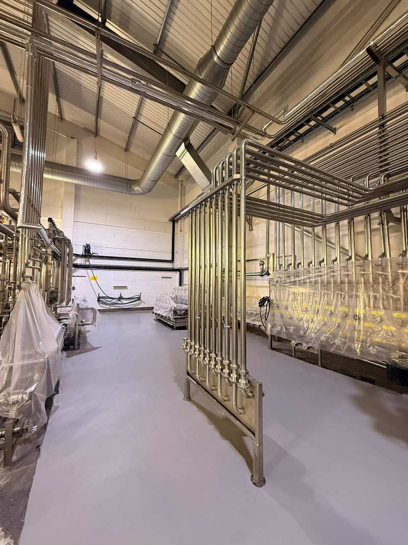 Finished grey resin floor beside a stainless steel pipe rack in a process plant