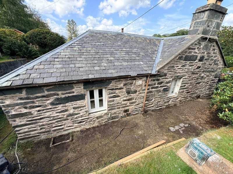 Single storey rubble stone cottage with a slate roof and stone chimney