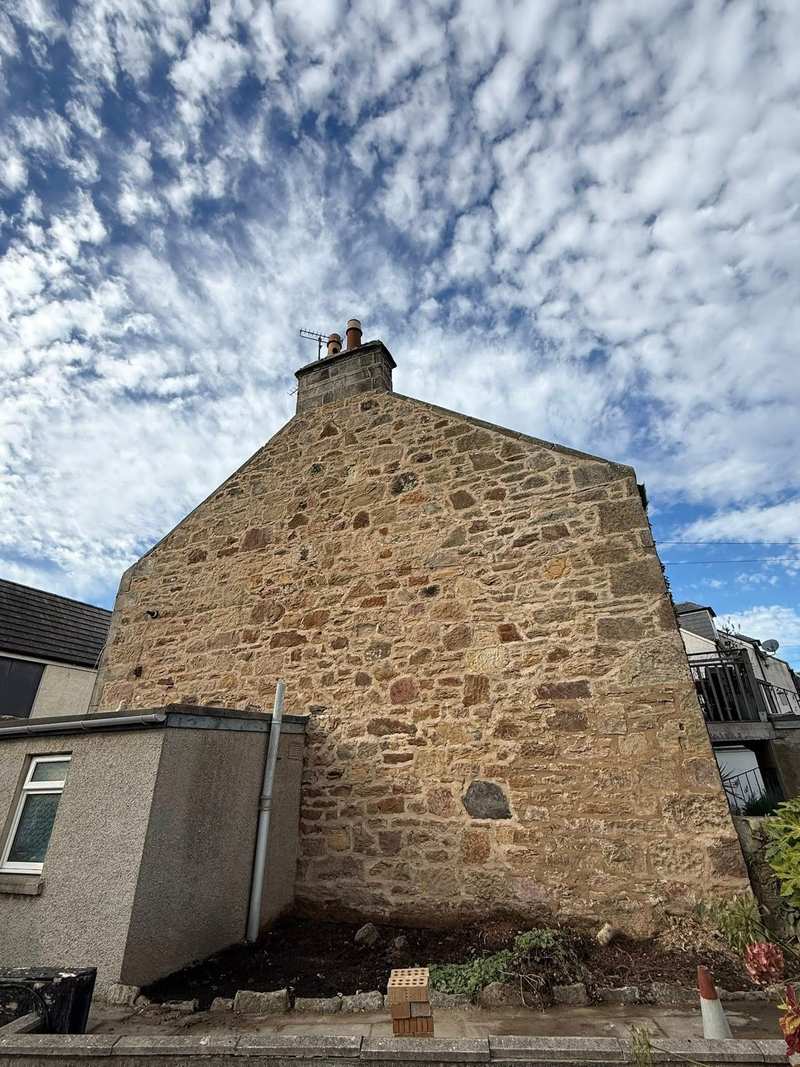 Stone gable end after cleaning and lime repointing, with the chimney stack at the apex