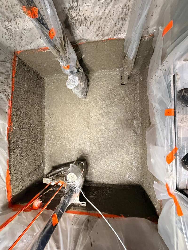 Cementitious waterproofing applied to the floor and wall upstands of a concrete lift shaft pit